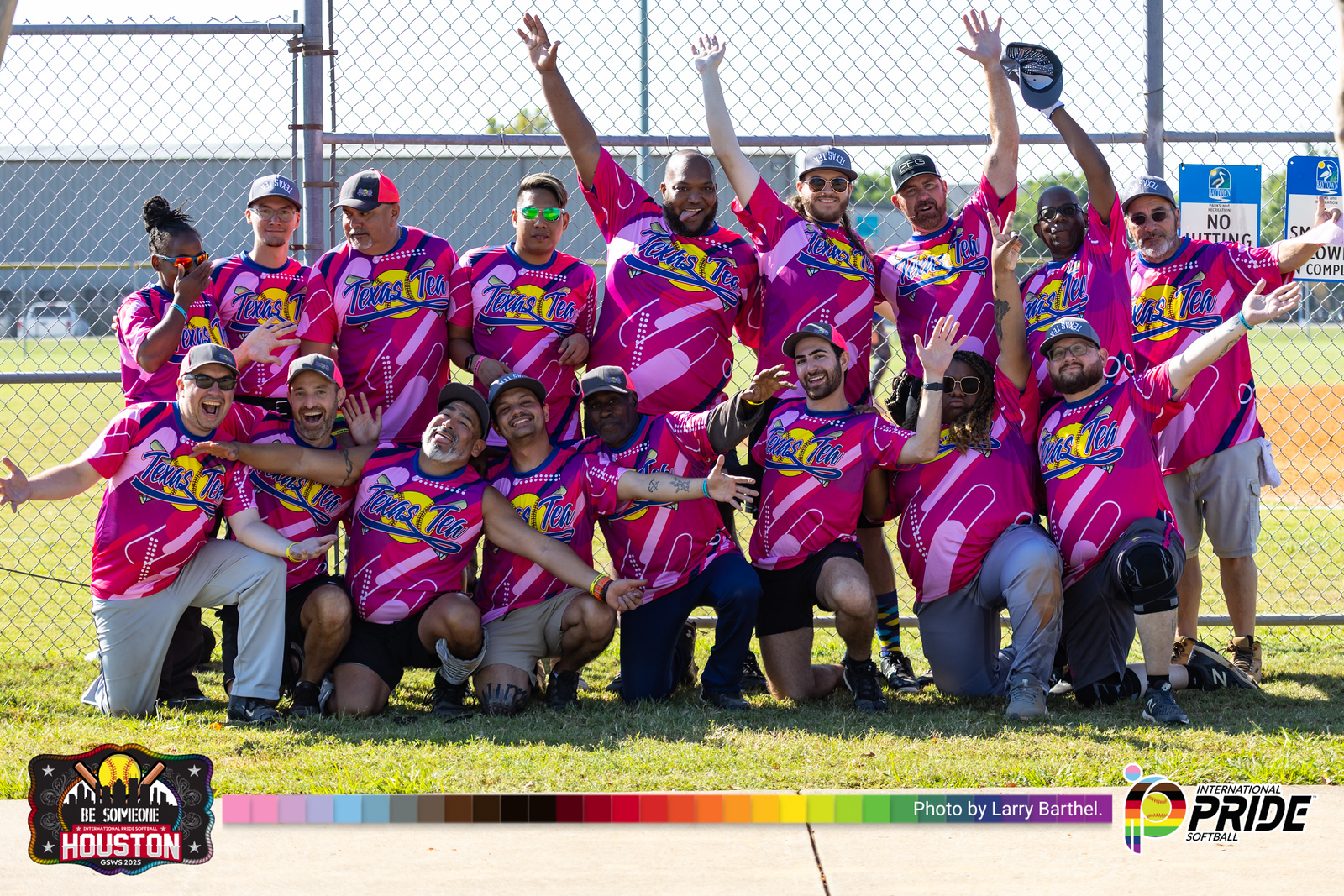 A diverse LGBTQIA2S+ softball team posing together in matching pink jerseys at the International Pride Softball tournament